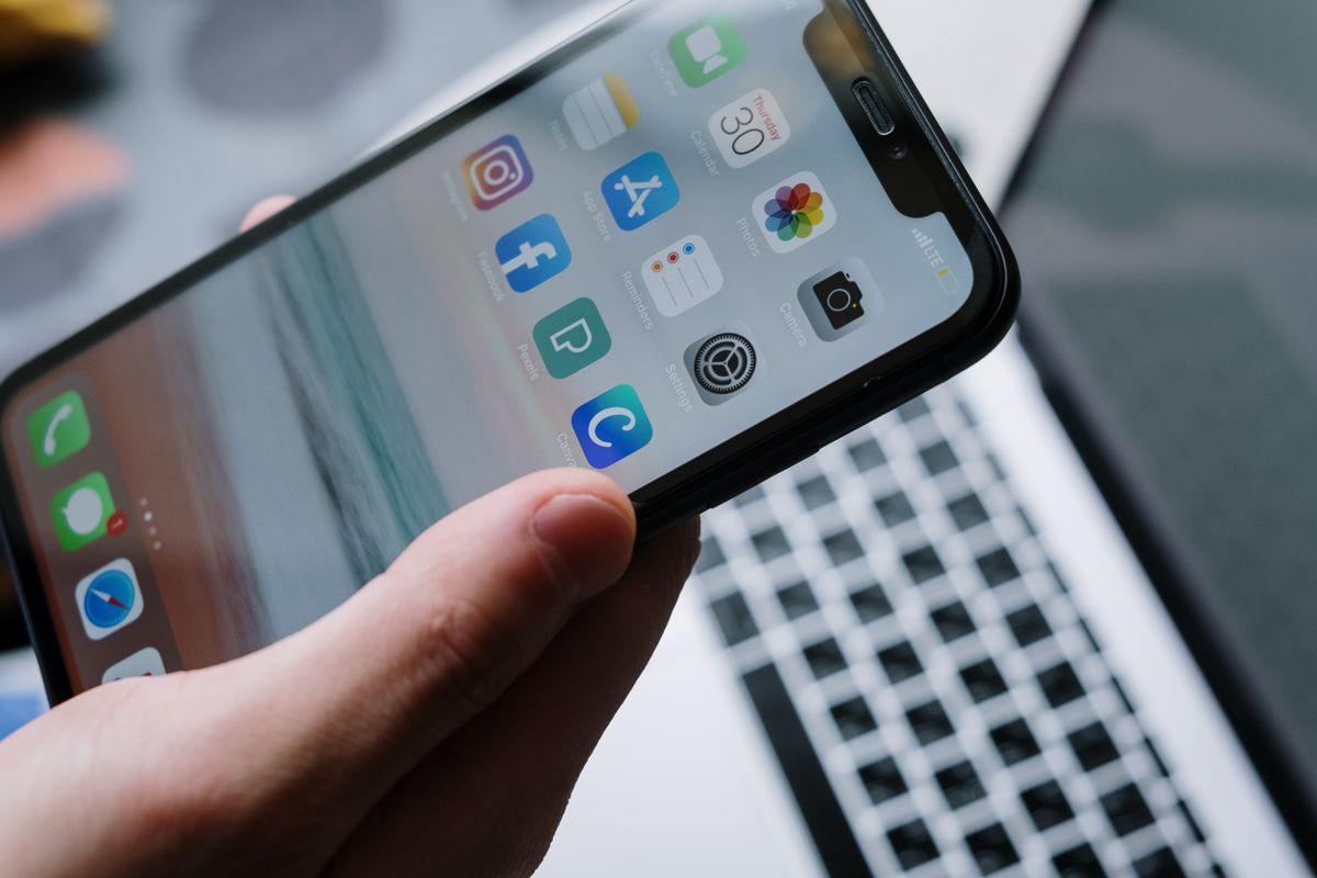 Smartphone with app icons in front of a laptop
